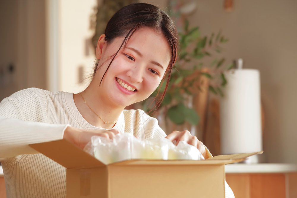 届いた商品の箱を開けて喜ぶ女性